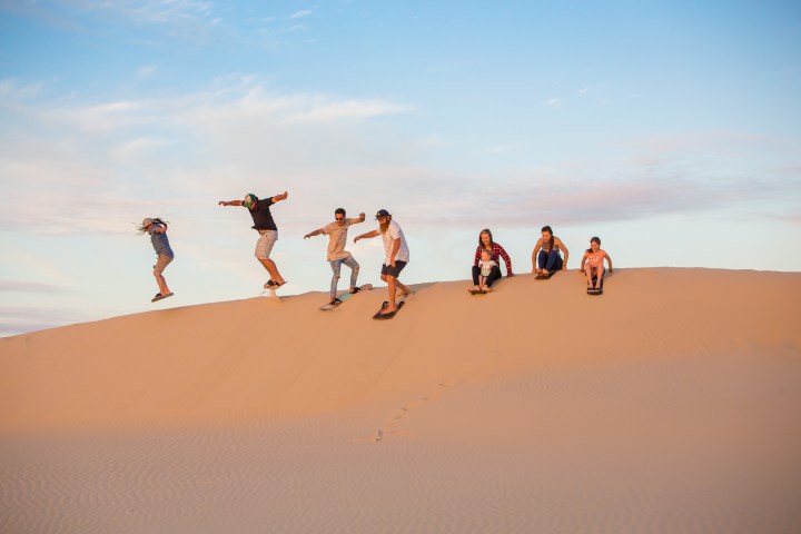 a group of people sandboarding with 4wd tours r us in anna bay, nsw