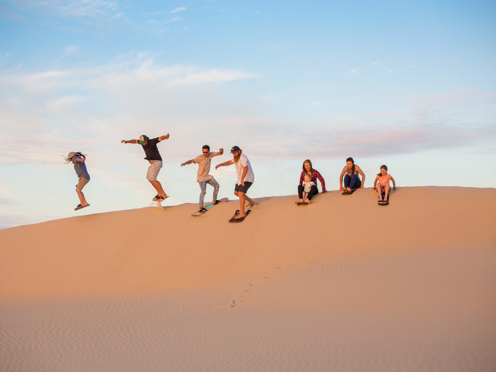 a group of people sandboarding with 4wd tours r us in anna bay, nsw