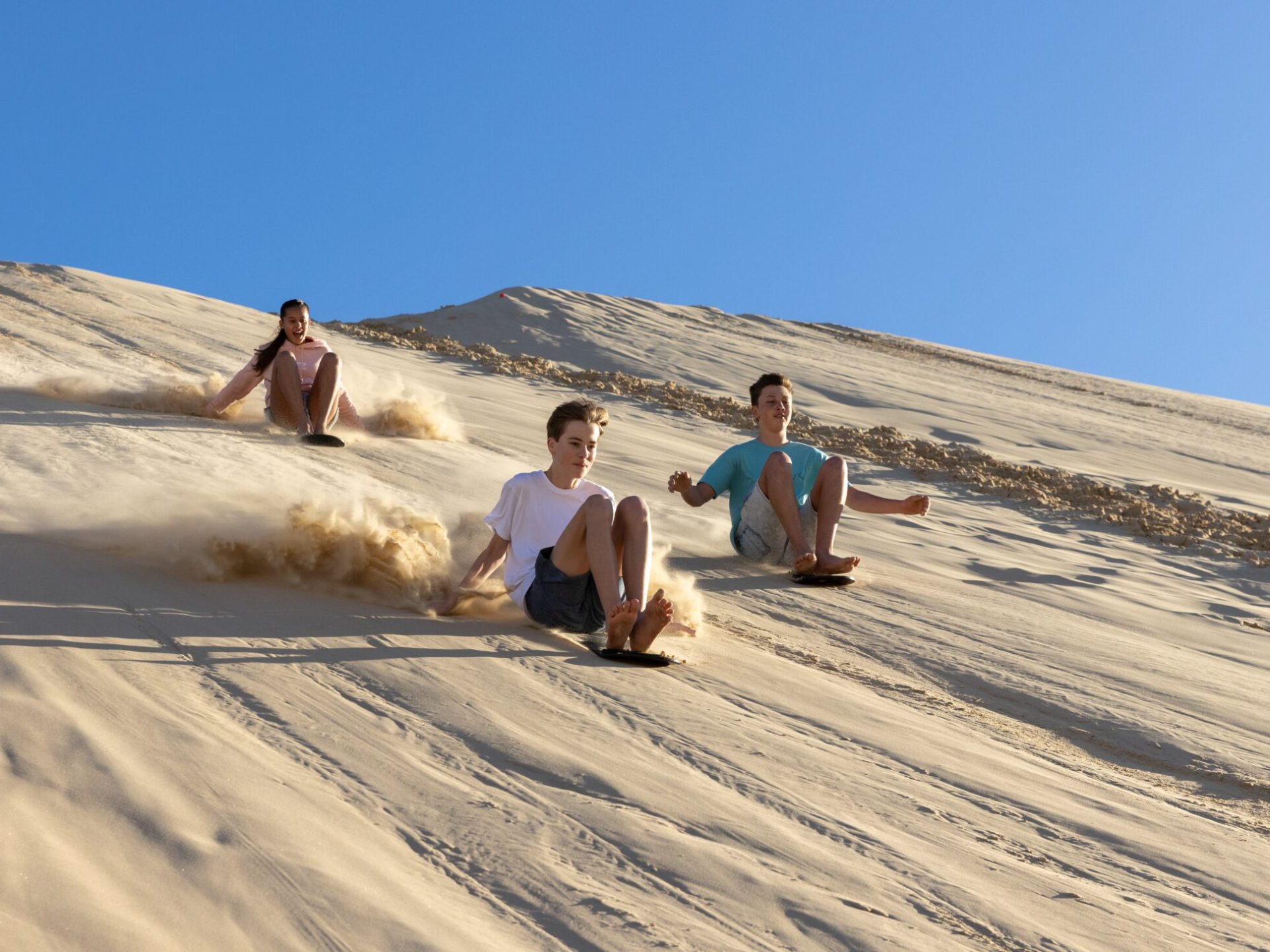 a group of people sandboarding with 4wd tours r us in anna bay, nsw